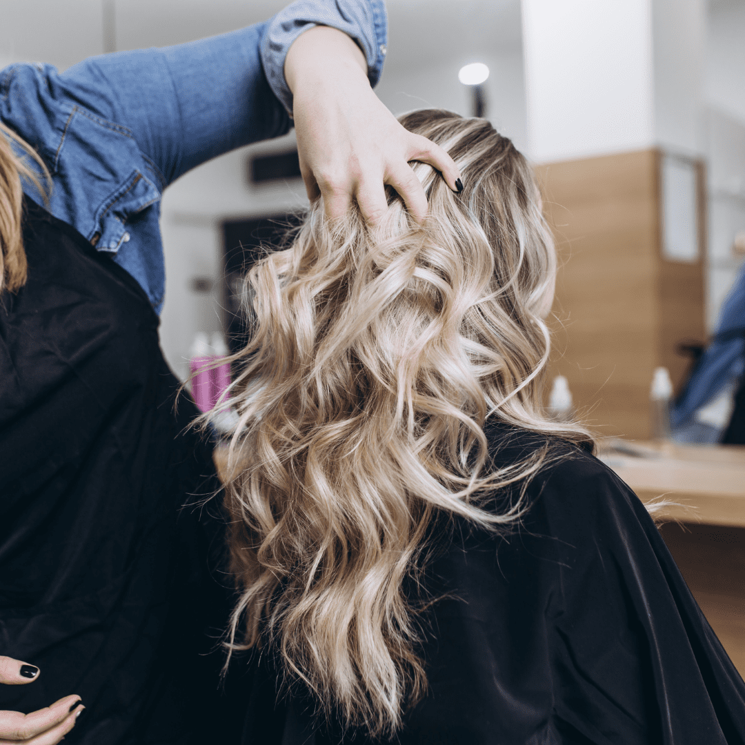 hairstylist runs hands through womans blonde hair
